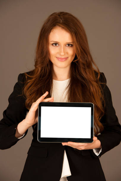 istock attractive business woman holds a tablet or smartphone wtih blank copy space for additional graphic or text 1203172117