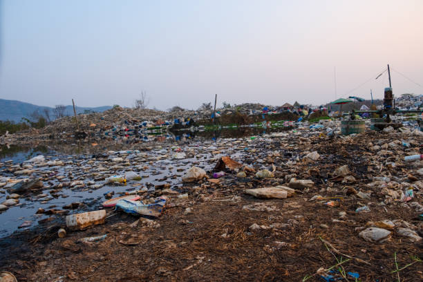 istock Polluted water and mountain large garbage pile and pollution at the sun is setting in the background, Pile of stink and toxic residue, These waste come from urban and industrial areas can not get rid of 1203172267