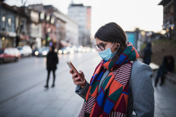 istock Woman With Mask Using Phone On The Street. 1203172270