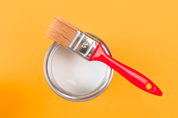 istock White Paint Can with Brush Top View On Yellow Background. 1203176113
