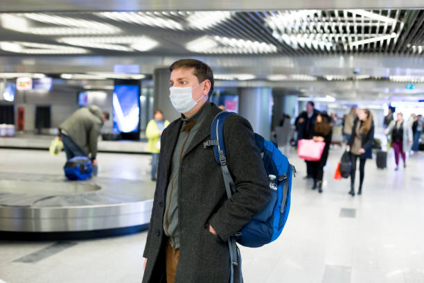 Young European man in gray coat, protective disposable medical