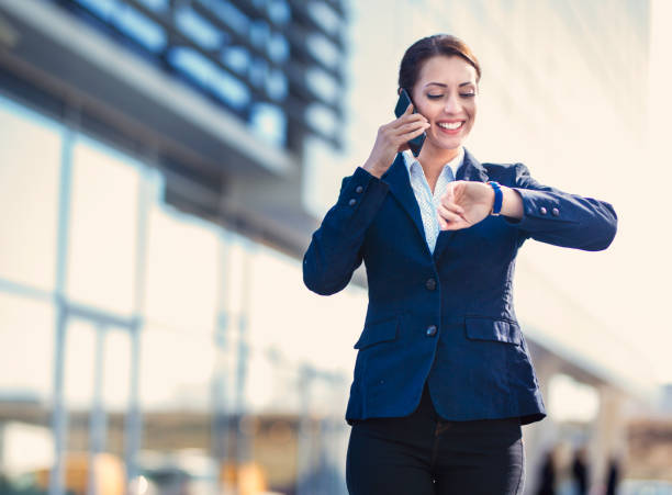 istock Businesswoman checking time on wristwatch while talking mobile phone 1203177155