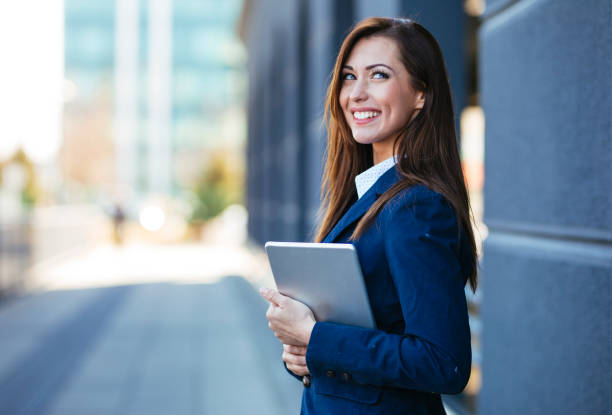 istock Businesswoman holding digital tablet and smiling 1203177345