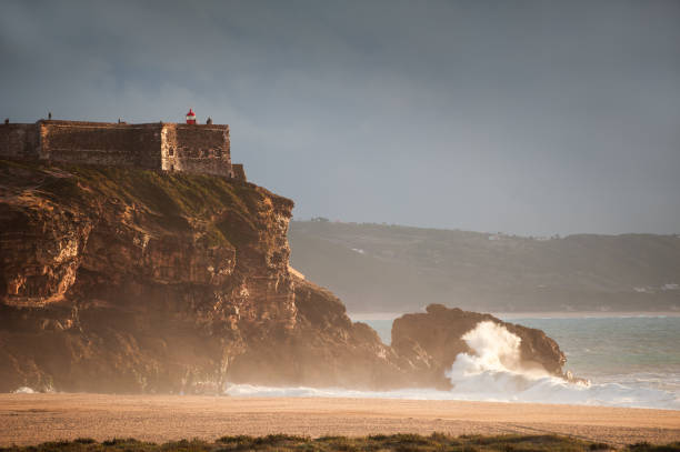 Lighthouse on the coast of Atlantic ocean in Nazare, Portugal Lighthouse on the coast of Atlantic ocean in Nazare, Portugal. Beautiful landscape at sunset nazare surf stock pictures, royalty-free photos & images