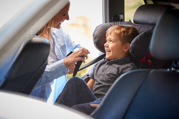 Mother Securing Son Into Rear Child Seat Before Car Journey Mother Securing Son Into Rear Child Seat Before Car Journey northern europe family car stock pictures, royalty-free photos & images