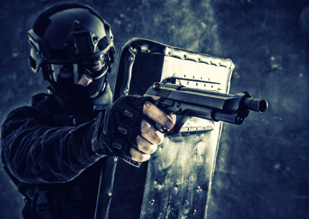 istock SWAT team fighter aiming pistol from behind shield 1203186717
