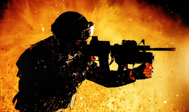 istock Soldier with rifle shooting on fiery background 1203186869