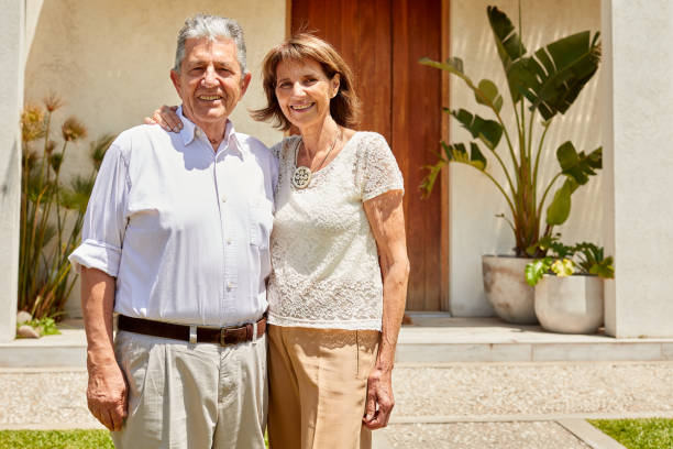istock Senior couple posing for the camera in front of their house. 1203187549