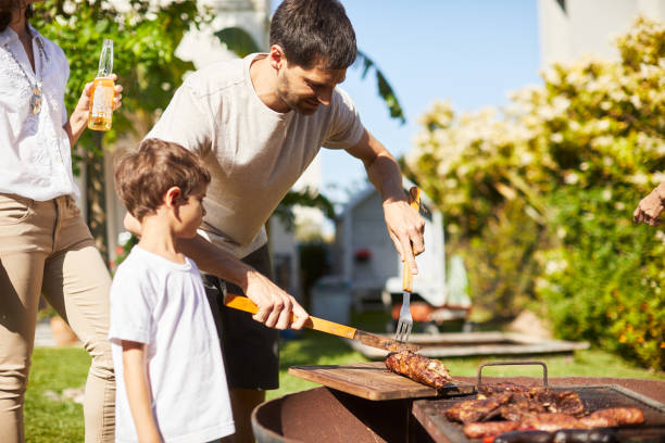Father grilling meat with his son in the garden.