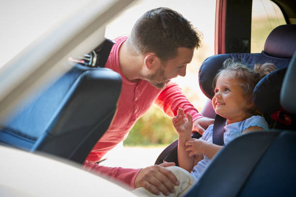 父親在汽車旅行前將女兒固定到後兒童座椅上 - 嬰兒安全座椅 圖片 個照片及圖片檔