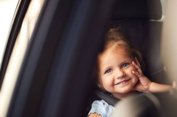 ritratto di ragazza seduta sul seggiolino di sicurezza per bambini durante il viaggio in auto guardando fuori dal finestrino - two girls only cheerful front view horizontal foto e immagini stock