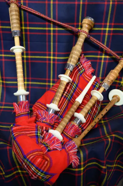 Scottish folk antique musical instrument bagpipes and colorful tartan fabric close up