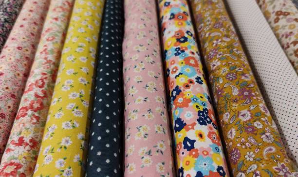 Rolls of fabrics mainly with small multicolored floral patterns.
