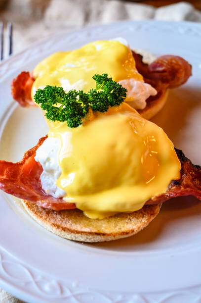 istock Weekend brunch in Scotland with two eggs benedict on homemade muffuns with roasted bacon and yellow hollandaise sauce. 1203189519