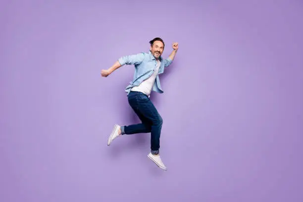 Full body profile side photo of crazy cheerful man jump have rest, relax run after spring time sales discounts wear good looking clothing isolated over violet color background