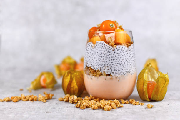 Healthy layered smoothie in glass with chia sees pudding, mixed with cereals and topped with orange persimmon and physalis fruits Healthy chia seed smoothie salvia hispanica plant stock pictures, royalty-free photos & images