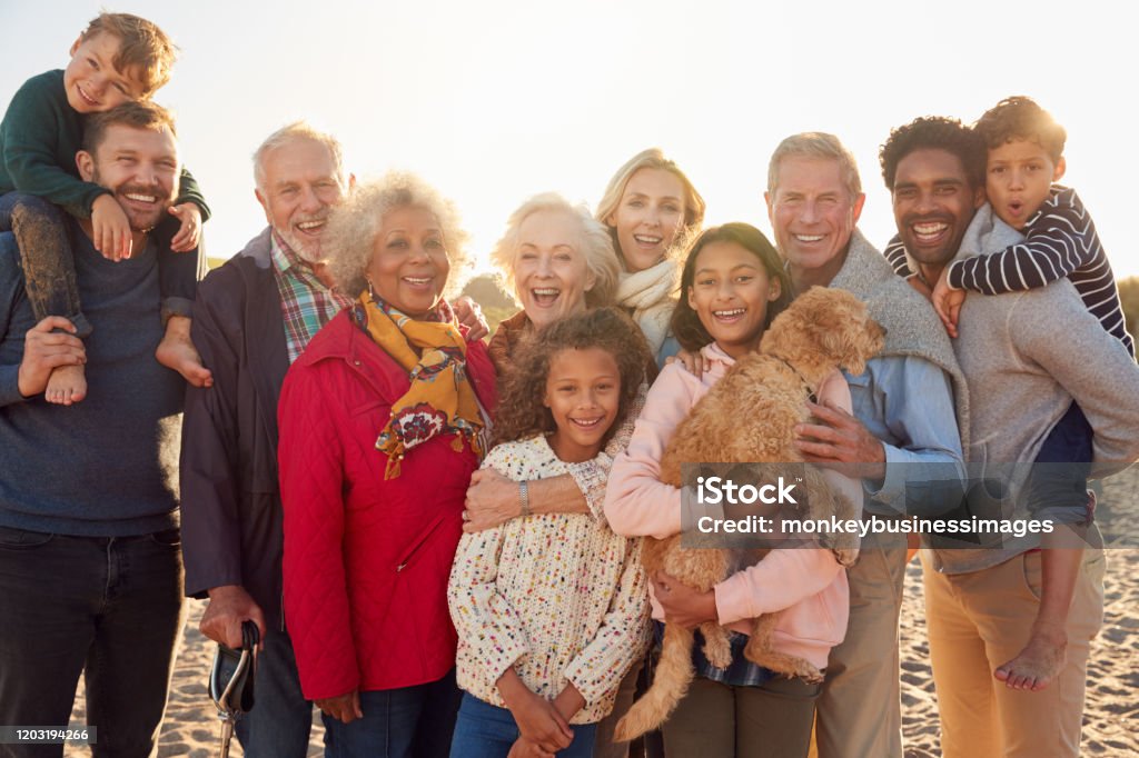 Portrait Of Multi-Generation Family Group With Dog On Winter Beach Vacation Family Stock Photo