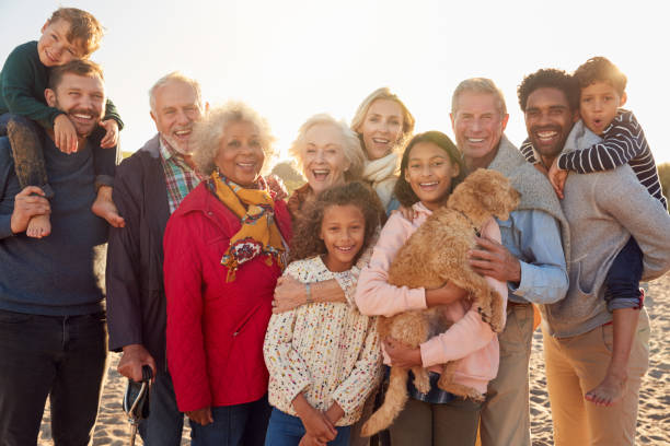 Portrait Of Multi-Generation Family Group With Dog On Winter Beach Vacation Portrait Of Multi-Generation Family Group With Dog On Winter Beach Vacation three generation family stock pictures, royalty-free photos & images