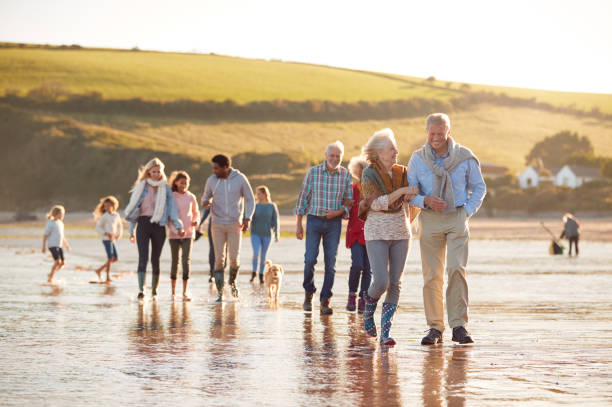 aktive mehrgenerationenfamilie mit hund, der im winterstrandurlaub an der küste entlang geht - grandparent multi generation family grandfather child stock-fotos und bilder