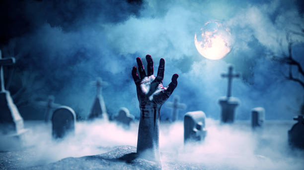 istock Zombie hand rising out of a graveyard in spooky night. 1203194493