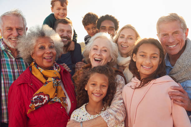 retrato de grupo familiar multigeneración en vacaciones en winter beach - grupo multiétnico fotografías e imágenes de stock