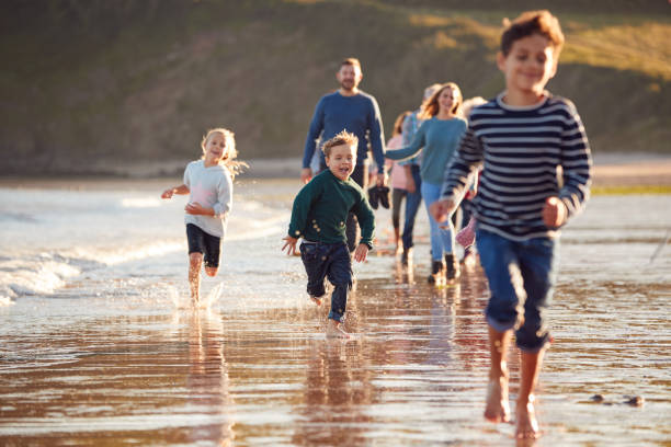 istock Children Run Ahead As  Multi-Generation Family Walk Along Shore On Winter Beach Vacation 1203194801