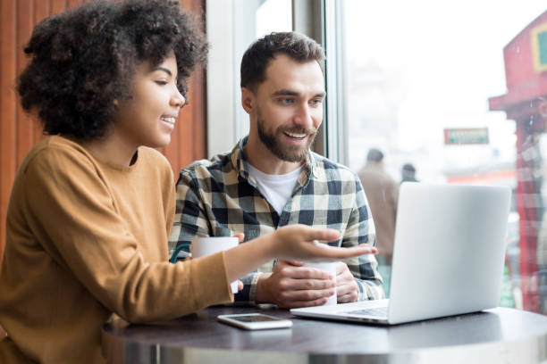 istock Happy young couple sitting and using laptop in cafe 1203195722