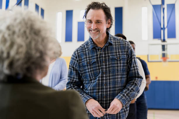 istock Mature man smiles at unrecognizable polling place volunteer 1203196301