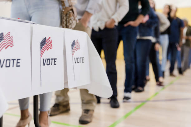 Low angle view of people lined up to vote A low angle view of a long line of people waitng to vote in the elections. voting stock pictures, royalty-free photos & images