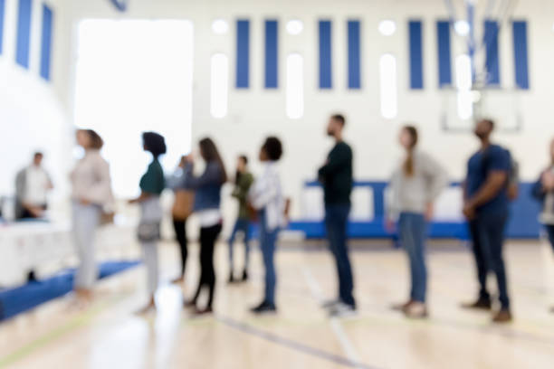 Defocused photo multi-ethnic group lined upto vote A defocused photo of a diverse gorup of people standing in line to sign up to vote. polling place photos stock pictures, royalty-free photos & images