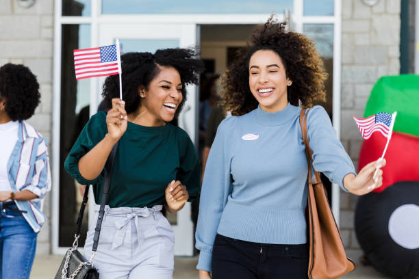 istock Mid adult female friends joyously exit polling place after voting 1203196342
