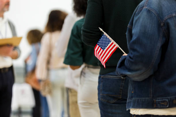 istock Diverse group in line to vote; one holds American flag 1203196350