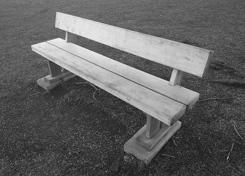 Black and white image of old wooden bench in park. Vintage style