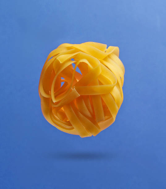 Minimalism italian food concept. Raw tagliatelle noodles on blue background. 3D photo with shadow