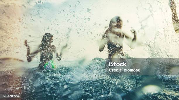 Friends Playing Together In The Sea Splashing And Diving During A Summer Sunset Stock Photo - Download Image Now