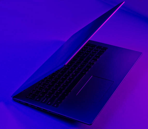 istock Modern laptop with vibrant gradient violet blue neon color lights. Minimal office surrealism concept. 1203211066