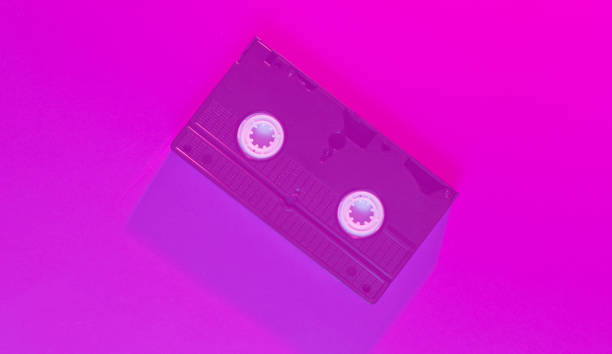 istock Retro wave style video cassette with neon pink-violet light. 80s. Top view 1203211137