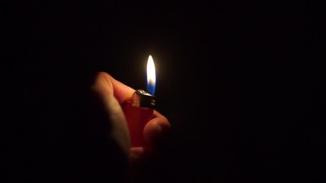 Close-up of ignition of a lighter in the dark during a concert.