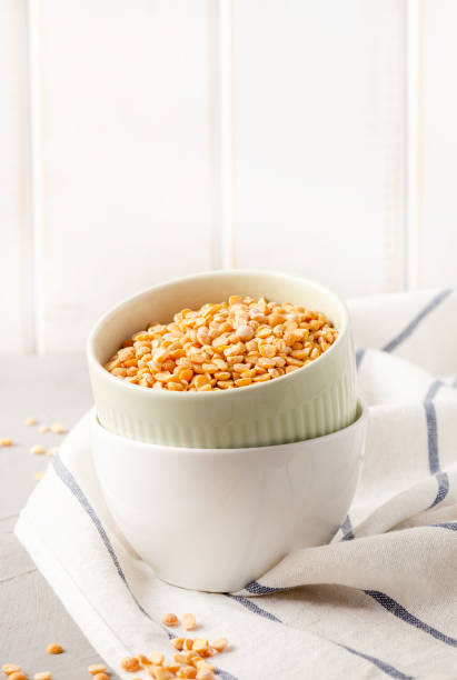 Dry uncooked peas in bowls on the kitchen table, copy space, light background.