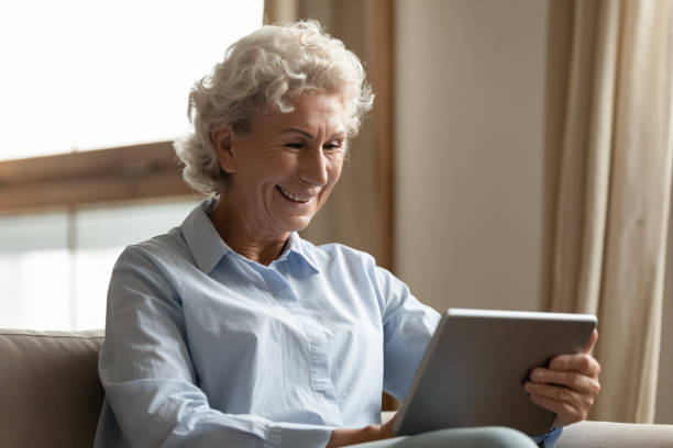 istock Happy older woman holding digital tablet, reading electronic book. 1203214389