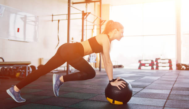 Athletic attractive woman doing an exercise lifting the leg up leaning on the medicine ball. Functional training concept Athletic attractive woman doing an exercise lifting the leg up leaning on the medicine ball. Functional training concept chest dip on athletic workout stock pictures, royalty-free photos & images