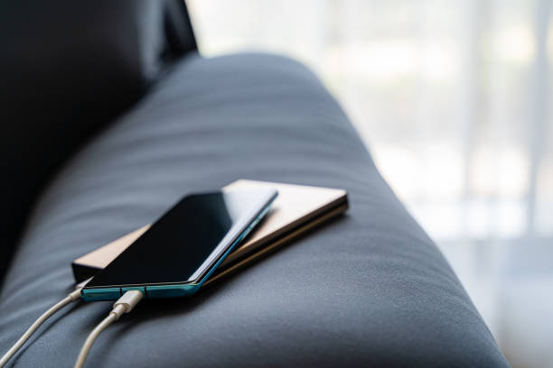 istock Mobile charging to smartphone from portable charger on Sofa. 1203220180