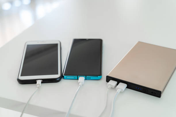istock Mobile phone connected to charger power bank on white table. 1203220205