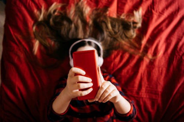 Girl using mobile phone in bedroom for making portrait