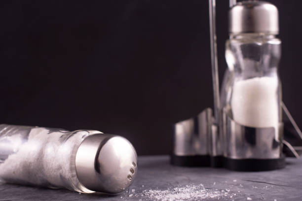 istock Glass salt shaker on the table. Spread salt. Free space for inscription. 1203224848