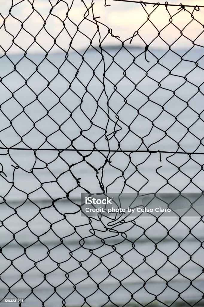 chain link fence crumpled chain link fence on a background of sea Boundary Stock Photo