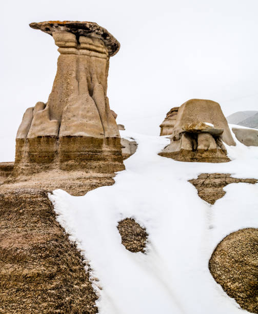 późny podmuch śniegu próbuje ukryć hoodoos w badlands. drumheller alberta, kanada. - steeple outdoors vertical alberta zdjęcia i obrazy z banku zdjęć