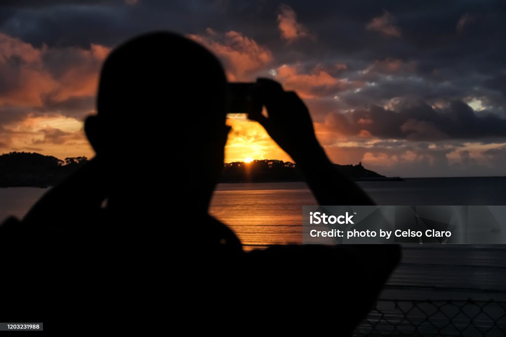 silhouette of man silhouette of man photographing the sunset People Stock Photo