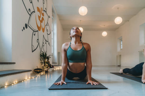 jeune femme adulte pratiquant le yoga au studio de yoga faisant la pose de salutation de soleil - bikram yoga pilates beautiful photos et images de collection