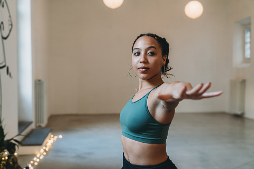 Portrait of a young adult woman practicing yoga in warrior pose. Mixed race, afro american young adult woman.